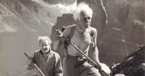 Lawren Harris hiking shirtless near Mount Temple in the Canadian Rockies with CBC producer Ira Dilworth. His easel and art supplies are on his back. 